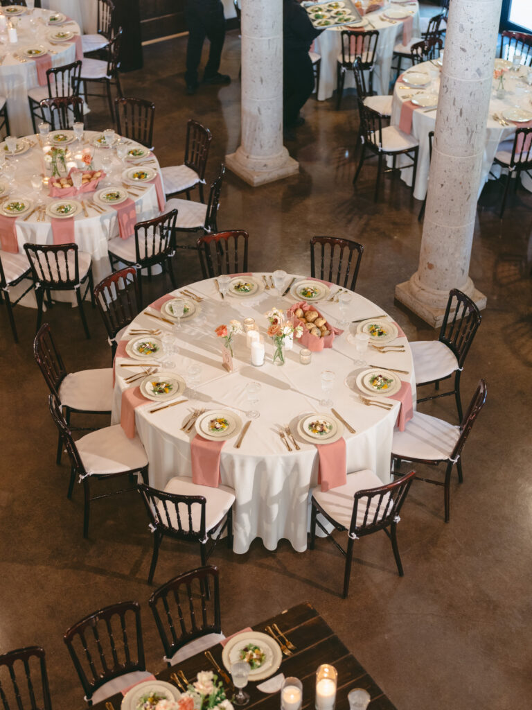 Overhead view of round wedding reception tables with blush napkins and floral centerpieces.