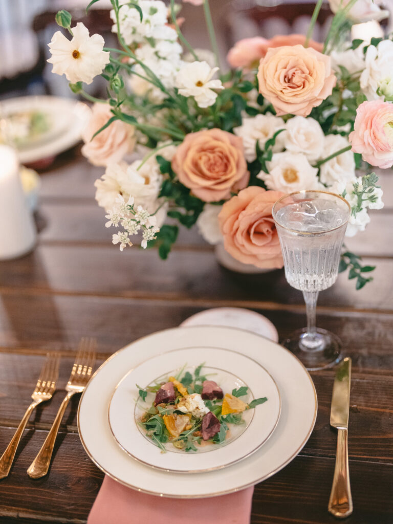 Wedding place setting with peach and white floral centerpiece