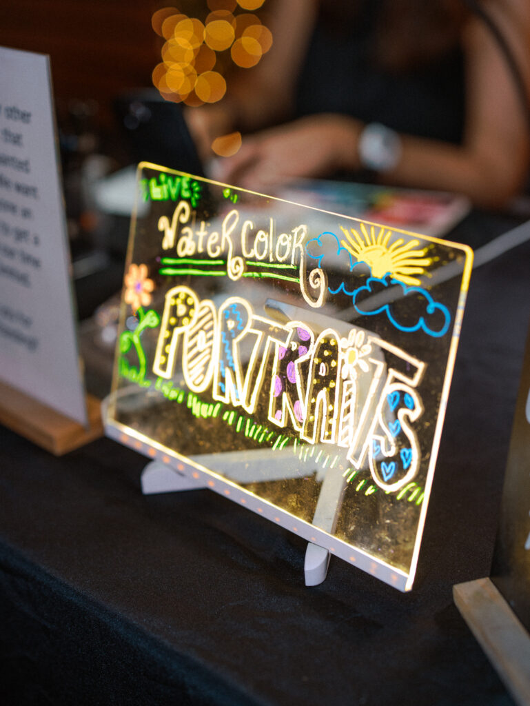 Colorful live watercolor portrait sign at a wedding reception