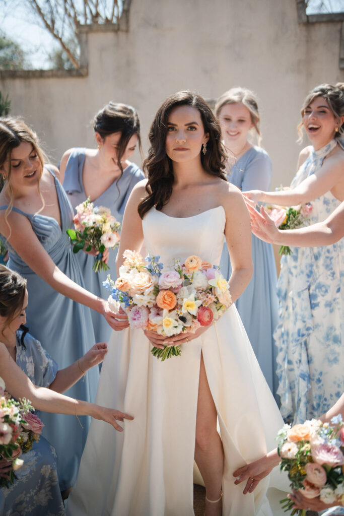Bride surrounded by bridesmaids, highlighting 2026 wedding trends in pastel gowns