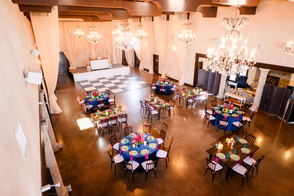 Spacious and beautifully decorated reception hall at Ma Maison showcasing elegant chandeliers and a festive table setting.