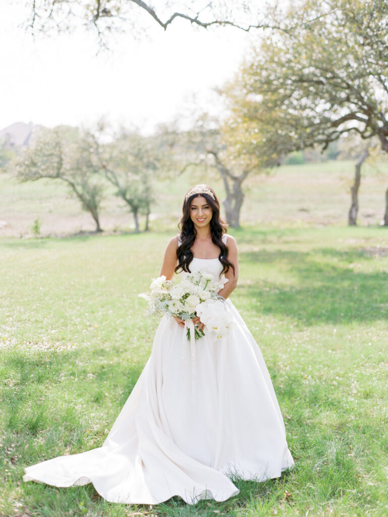 bride standing in grassy field 