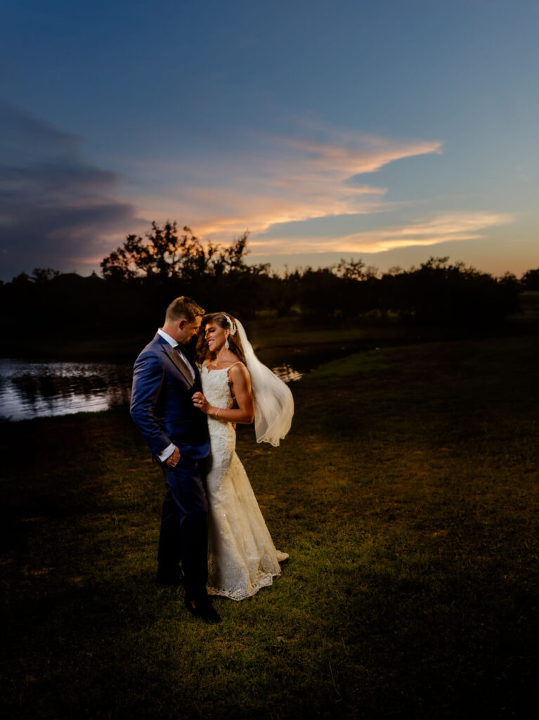 bride and groom standing on grass at sunset at Ma Maison