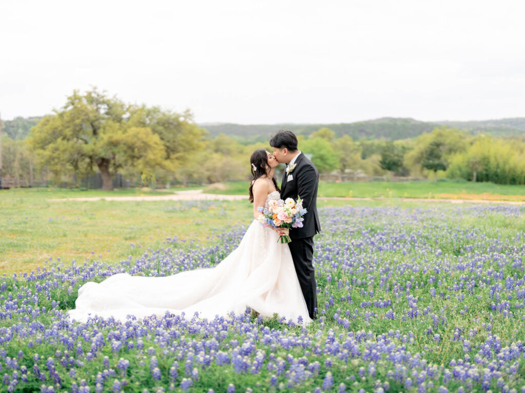  A stunning bride and groom share an intimate kiss among vibrant Texas wildflowers, a picture-perfect scene for an Austin wedding videographer