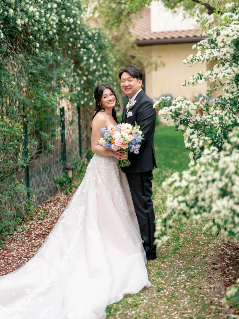 A glowing bride and groom smile amidst lush greenery, a timeless moment captured by an Austin videographer.