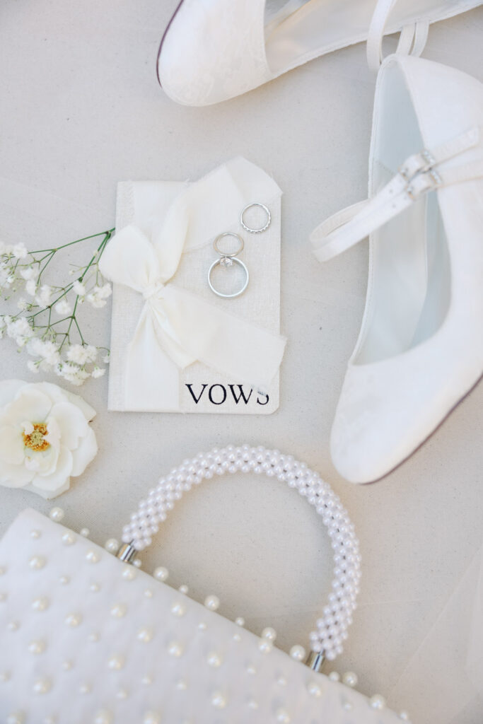 Flat lay of wedding ring, vows, shoes and bag