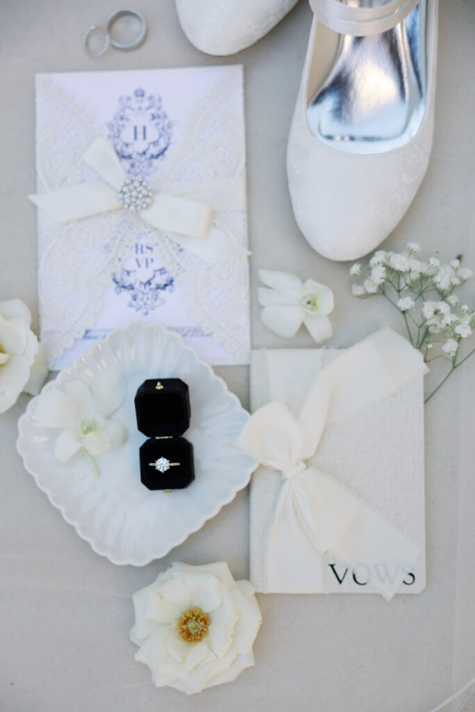 Flat lay of wedding ring, invitation, vows and shoes