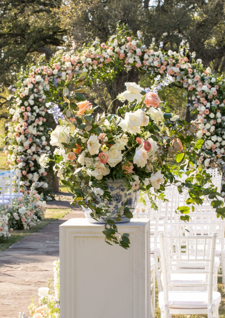 Ceremony floral pedestal arrangement in front of an arch