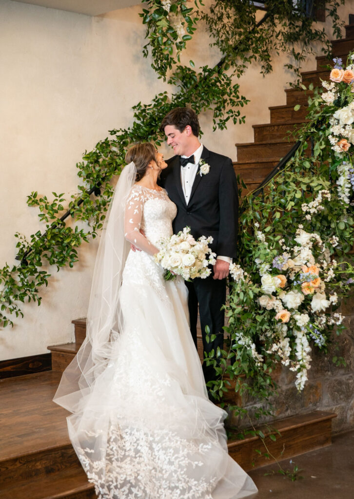 Bride and groom posing on a staircase decorated with greenery