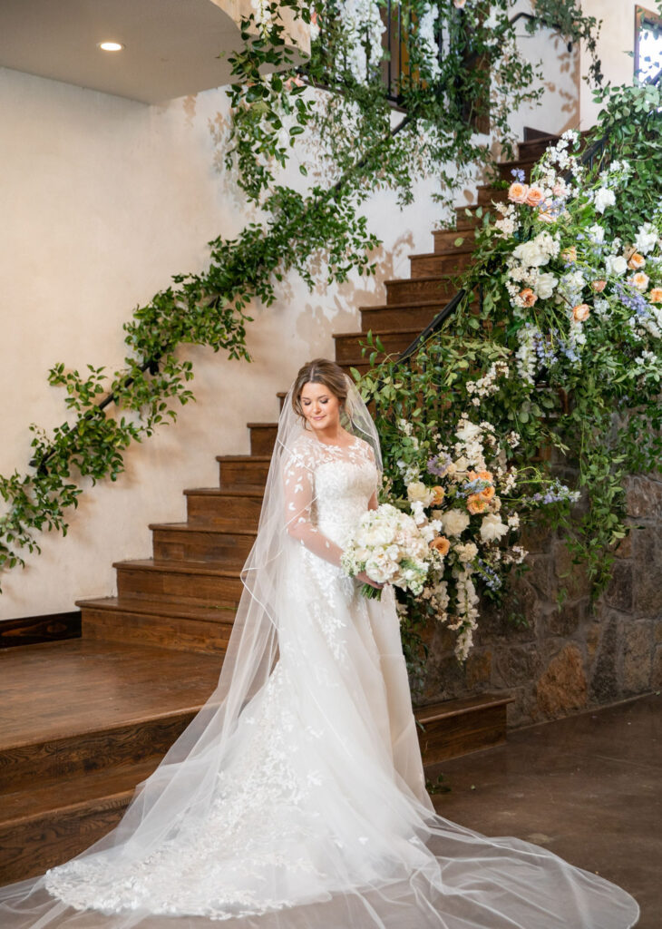 Bride standing on a floral-adorned staircase at an Austin wedding venue
