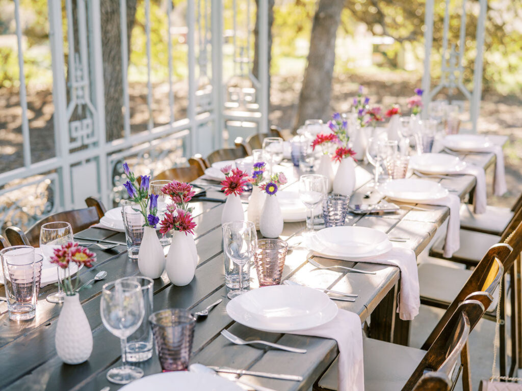 tablescape with plates, potted flowers, and glasses at Ma Maison wedding venue