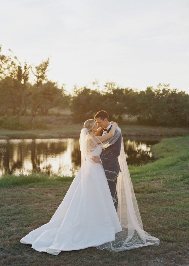 bride and groom kissing next to pond at Ma Maison wedding venue