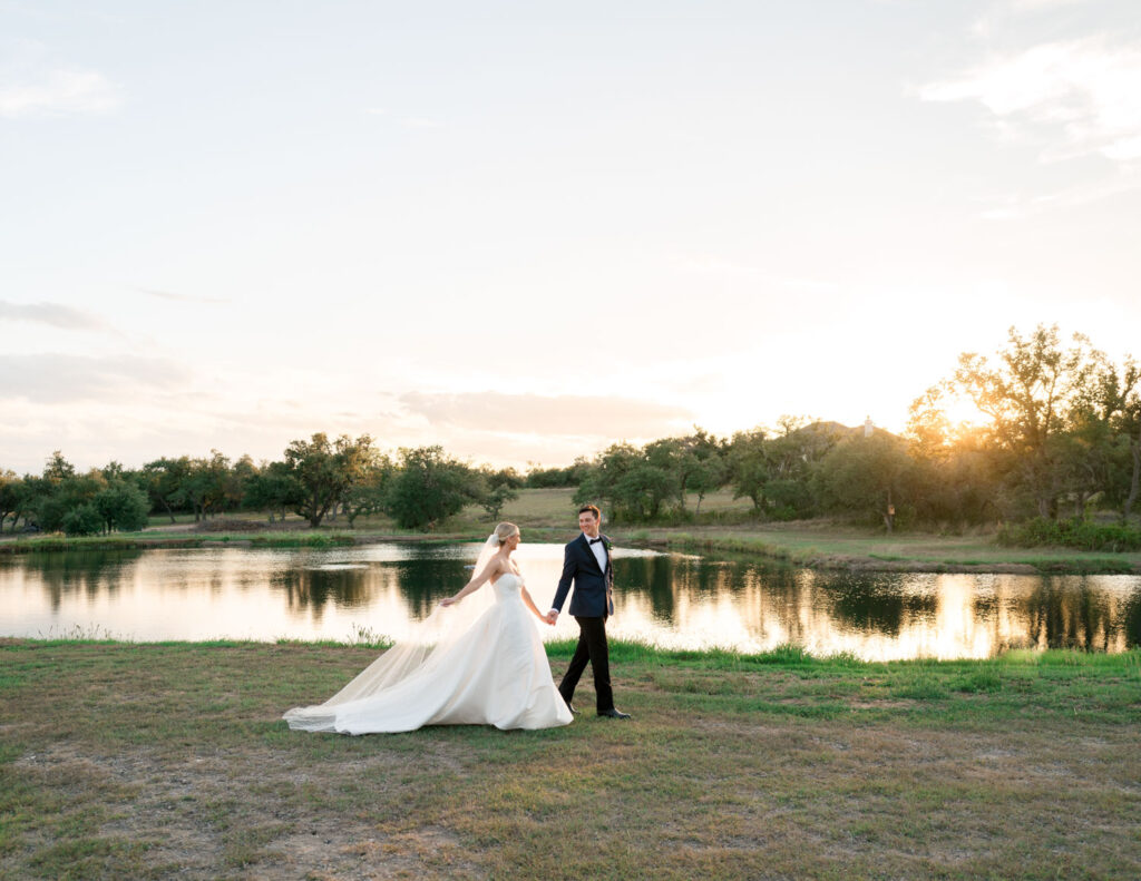 bride and groom walking in front of pond at wedding venue in Austin