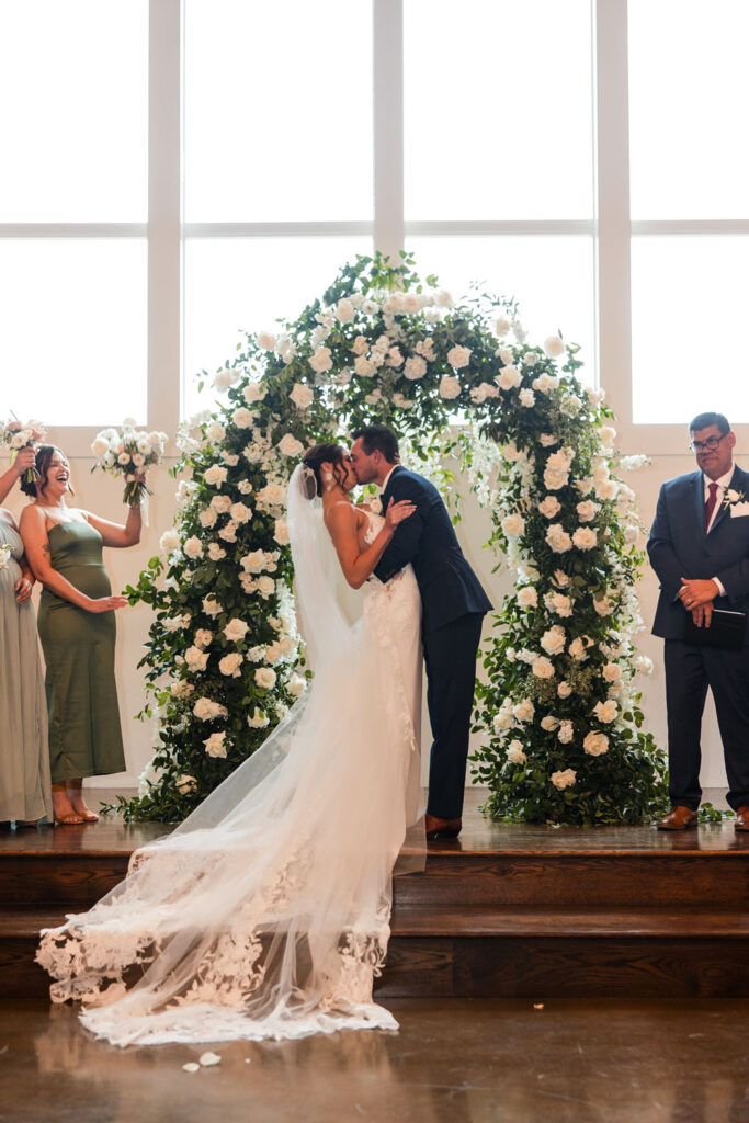 The bride and groom celebrate their wedding ceremony with a romantic dip and a kiss at Ma Maison’s elegant indoor chapel