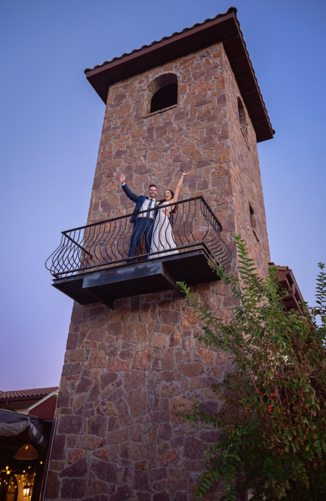 Bride and groom celebrating on stone tower balcony