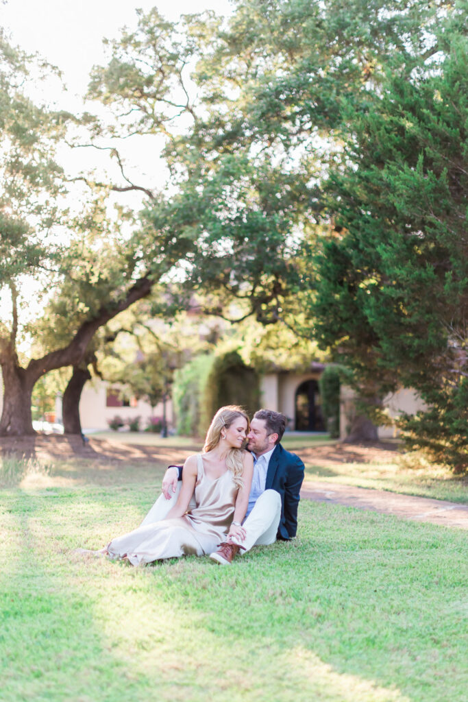 Romantic couple sitting under oak trees at Ma Maison