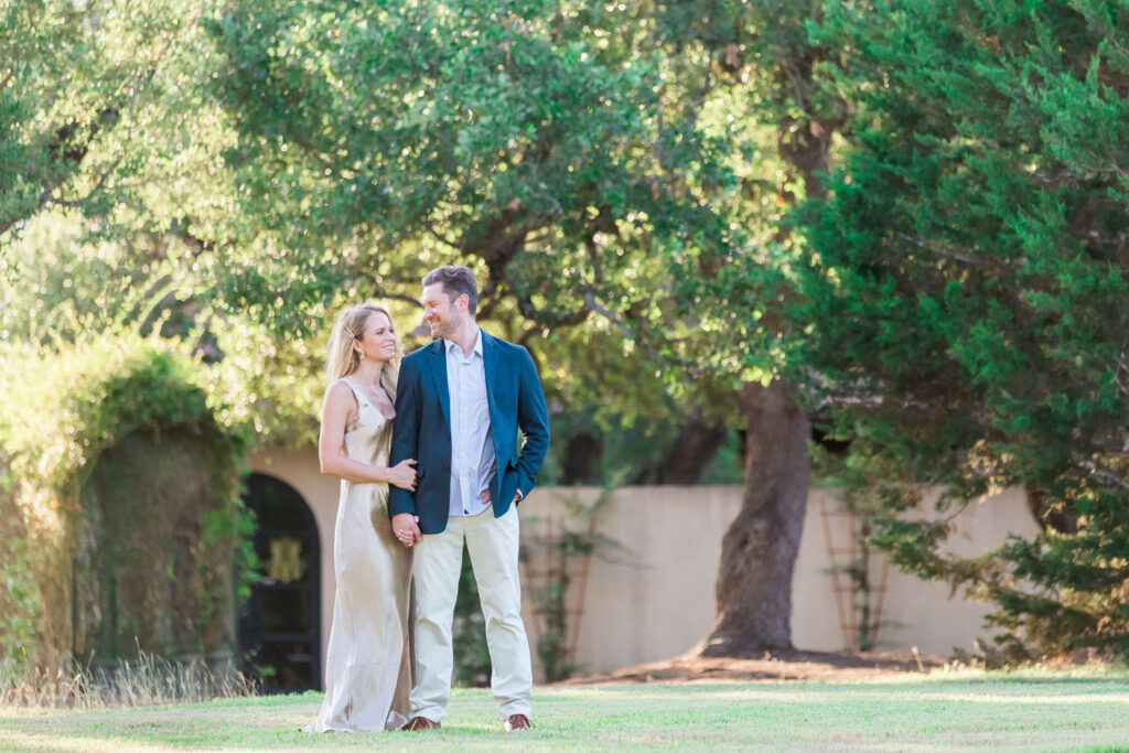 Engaged couple walking hand in hand through Ma Maison grounds