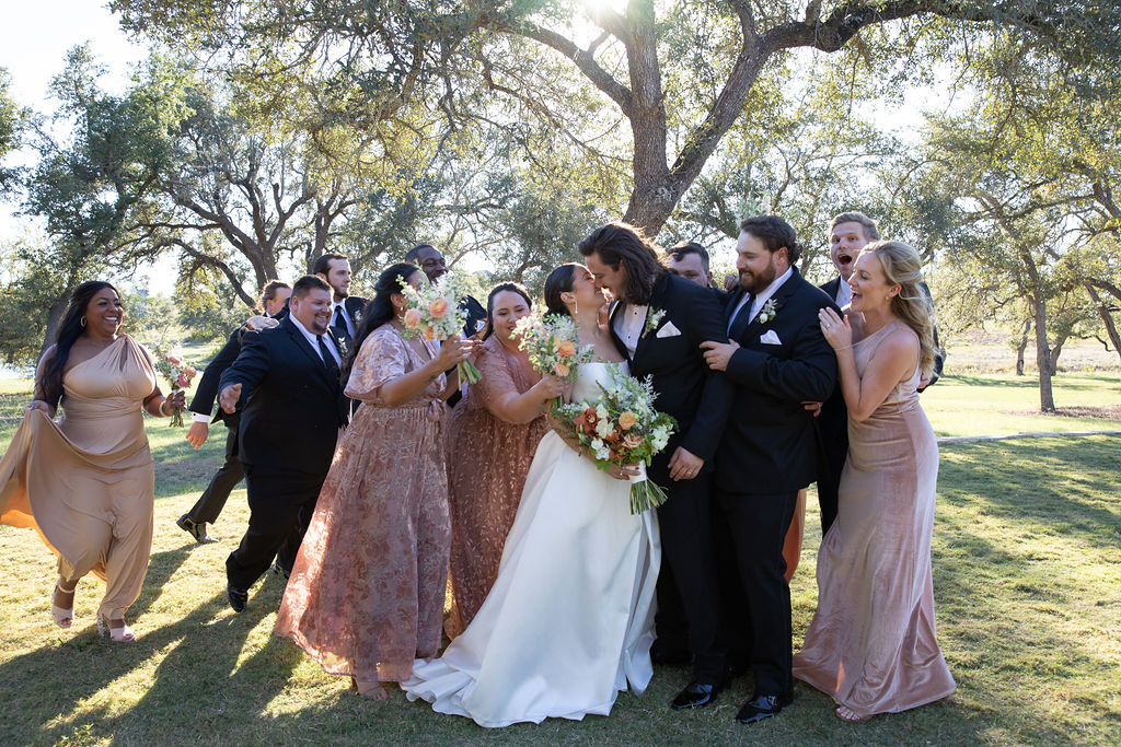 Bride and groom surrounded by bridal party in elegant black-tie wedding outfits