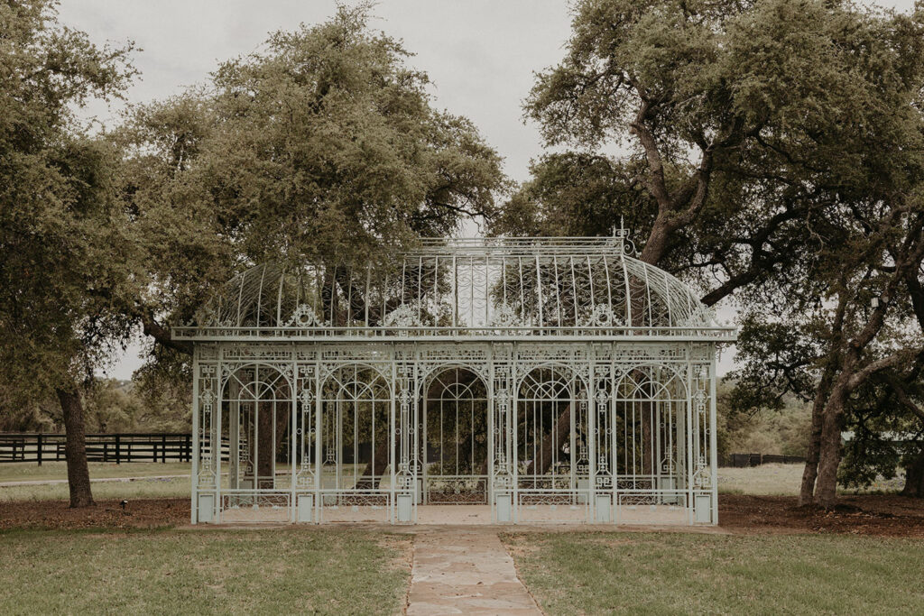The Green Cathedral at Ma Maison, a romantic wrought-iron structure surrounded by trees—an ideal choice for couples looking for budget wedding venues in Austin with European-inspired design.