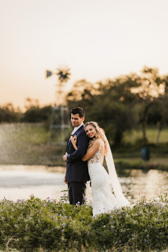 Bride and groom embracing by the lake at sunset at a Dallas wedding venue near Austin