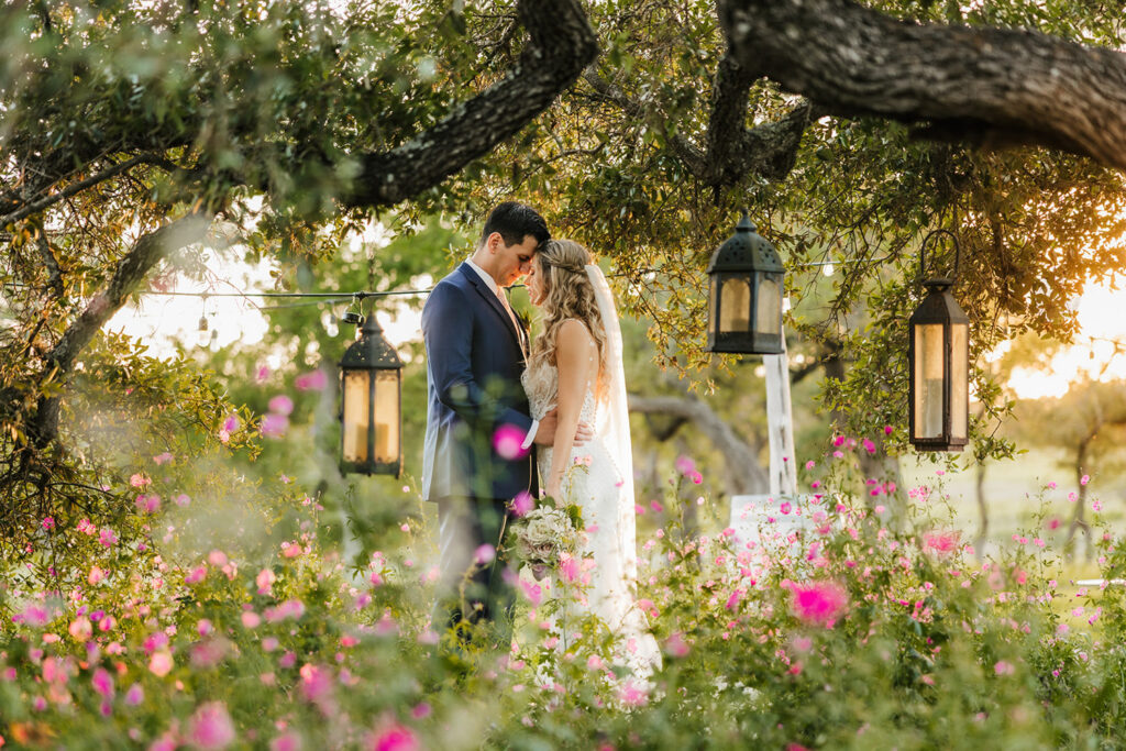 Romantic garden portrait of newlyweds surrounded by flowers