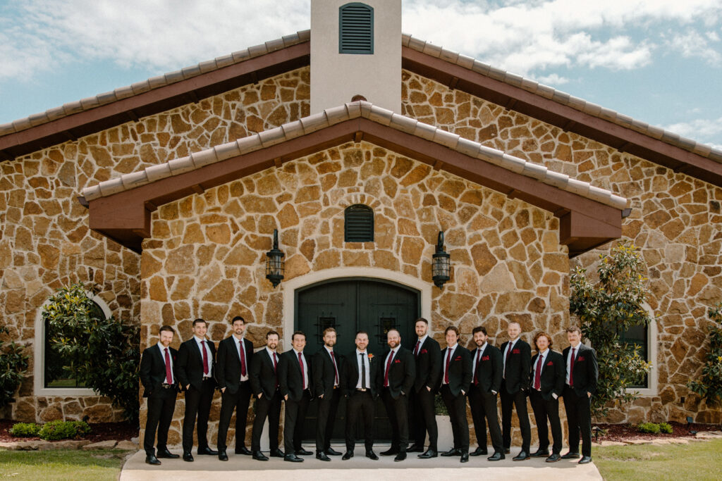 villa style dream wedding venue in Dripping Springs, Texas with groom and groomsmen in front of it