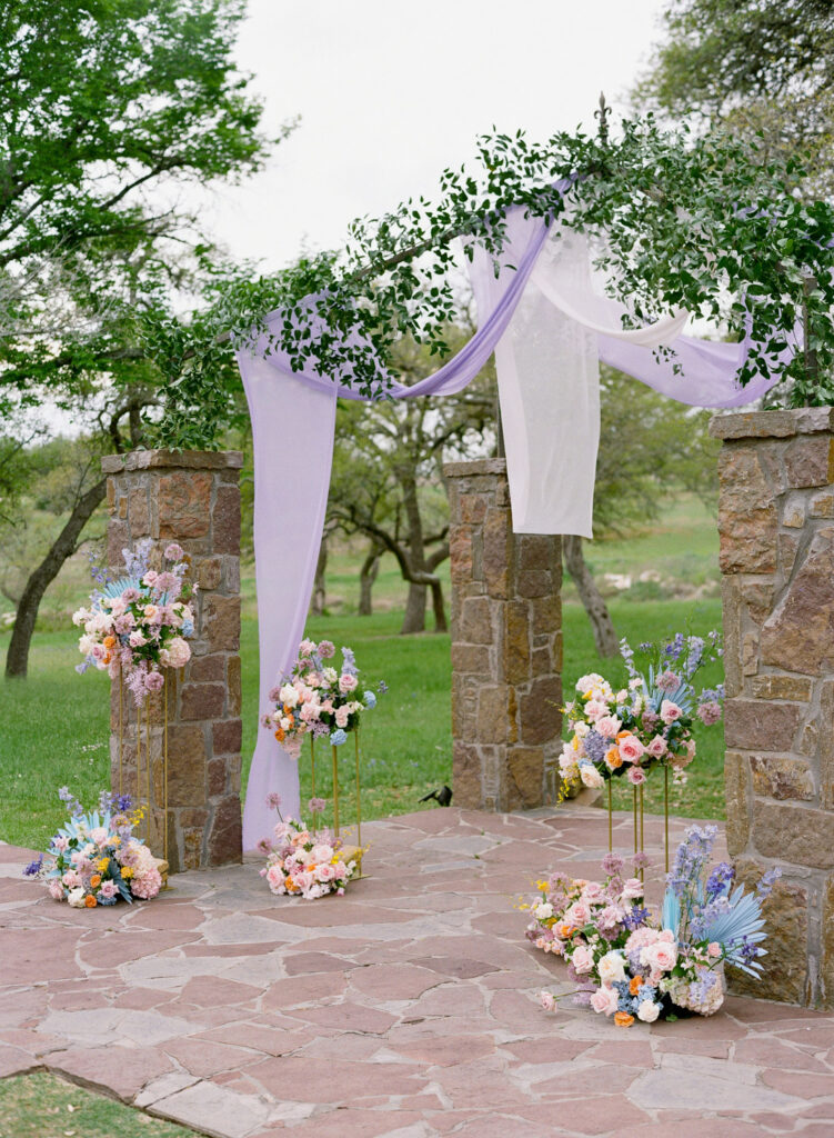 Archway decorated with lavender draping and lush pastel florals