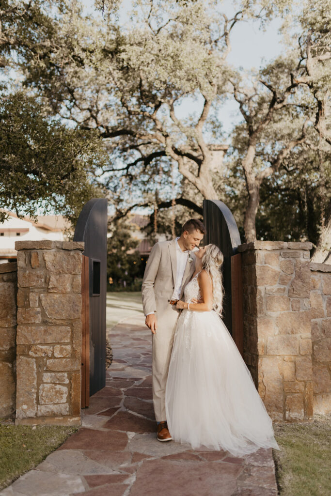 Couple kissing at rustic stone gate on wedding day