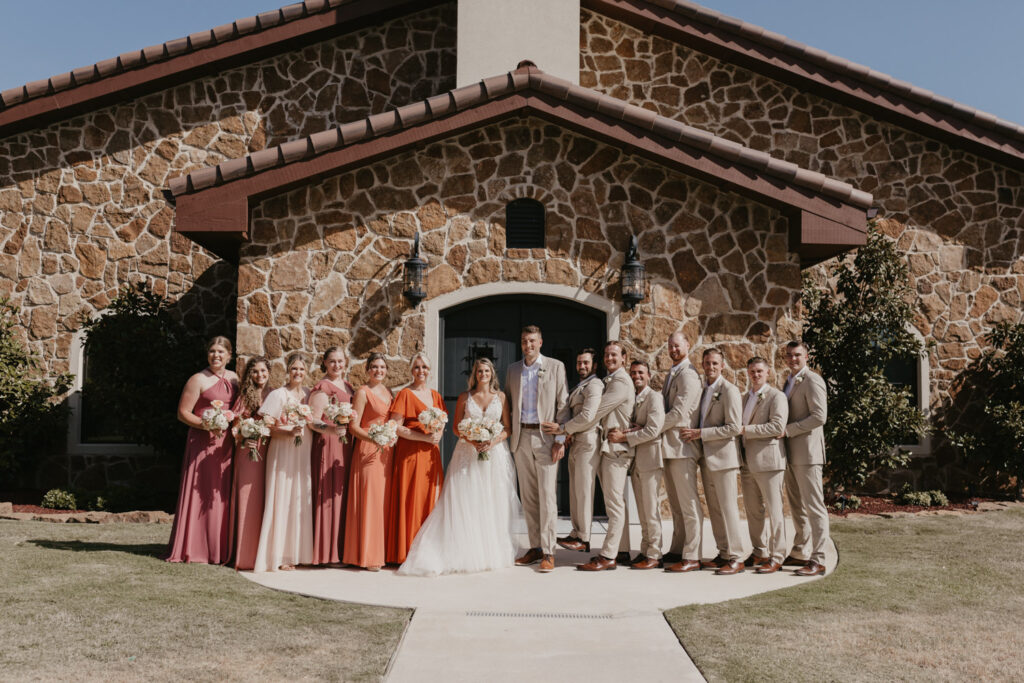 Wedding party in warm toned dresses and tan suits