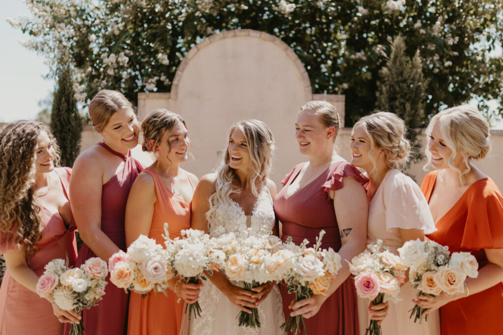 Bride laughing with bridesmaids in fall color dresses