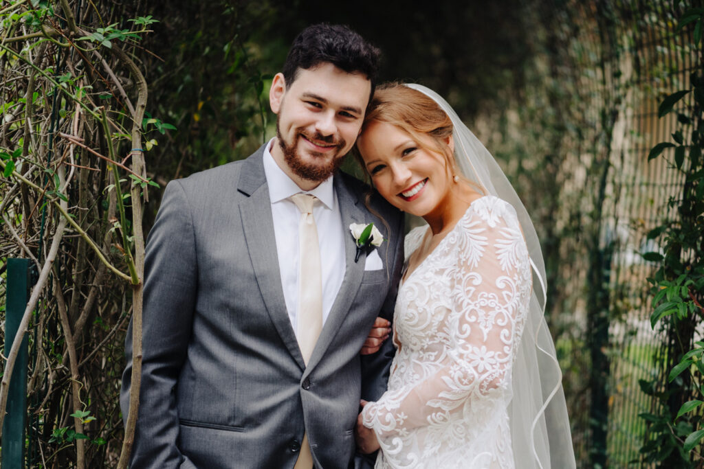 Bride and groom smiling and posing outdoors after hair and makeup session by a professional hair and makeup artist in Austin.