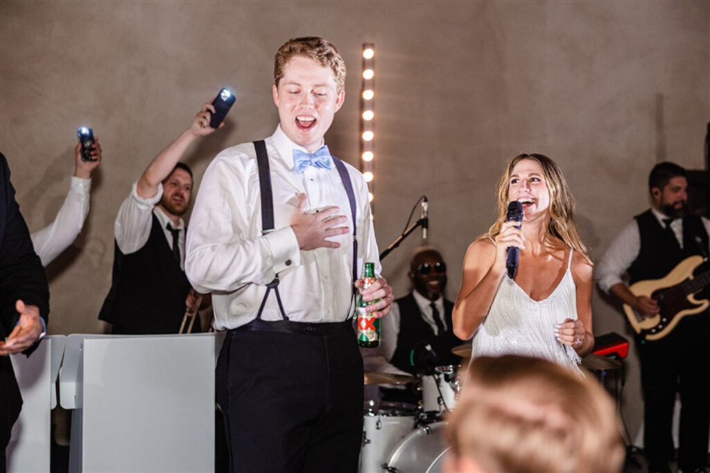 groom and bride singing in front of band on their wedding day