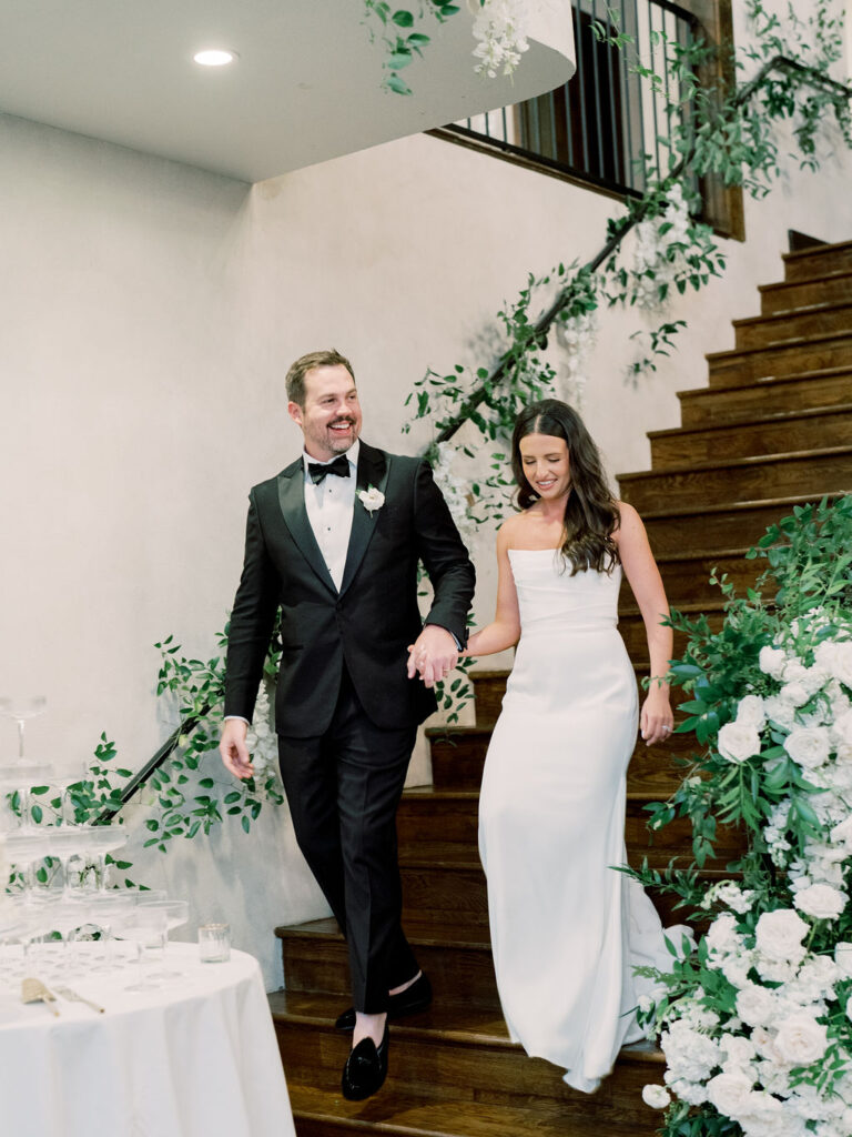 Couple descending staircase with florals at Houston wedding venues