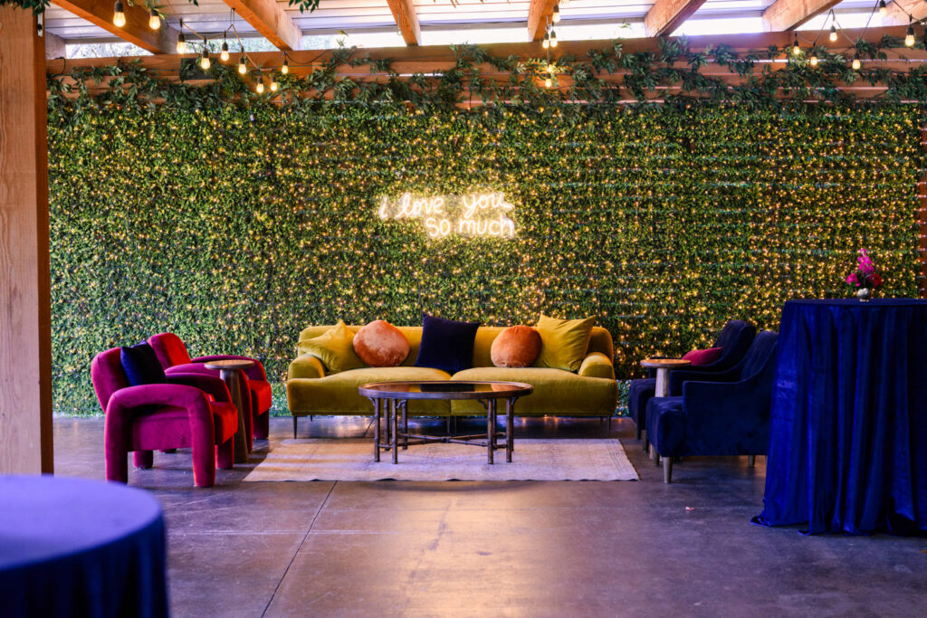 Chic lounge area with velvet seating and greenery wall at an intimate wedding venue in Austin