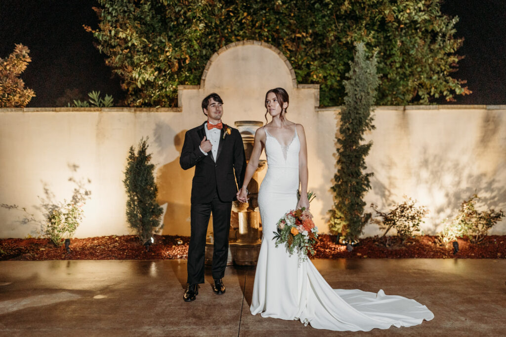 Elegant bride holding bouquet, standing with groom at Italian destination wedding venue