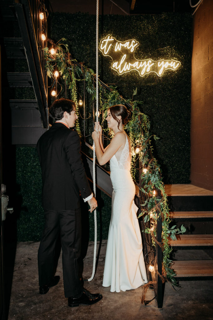 Couple ringing bell under a neon 'it was always you' sign at Italian destination wedding
