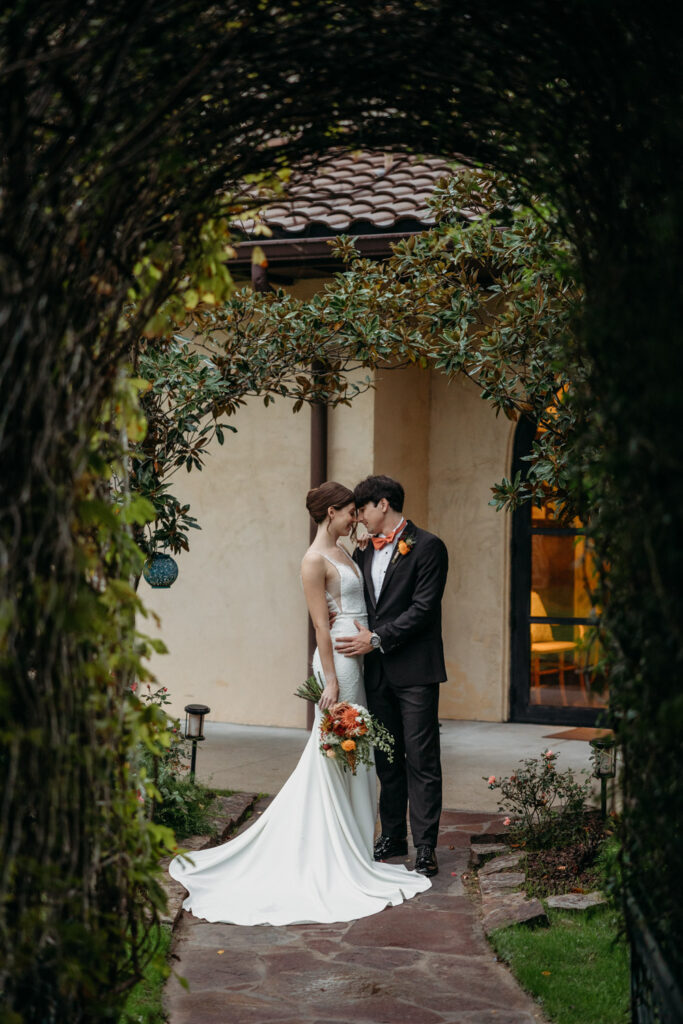 Bride and groom standing under vine-covered archway