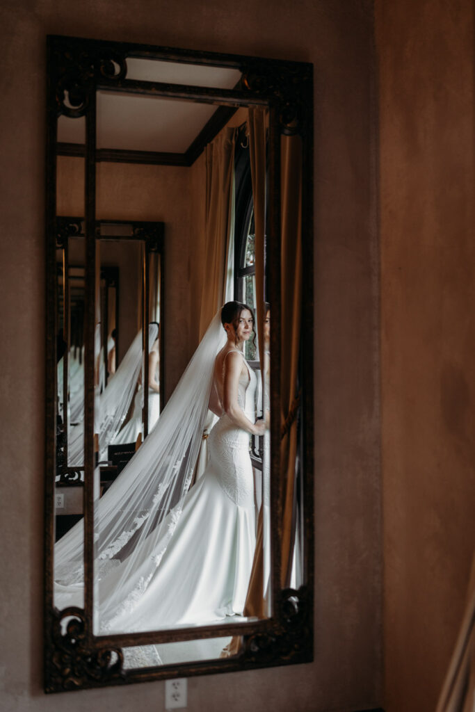 Reflection of bride in mirror as she poses in her wedding gown