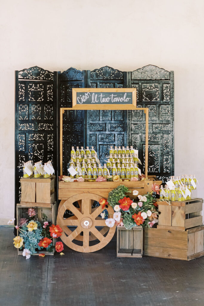 A charming Italian-inspired wedding favor station at Ma Maison featuring bottles of olive oil and rustic floral décor