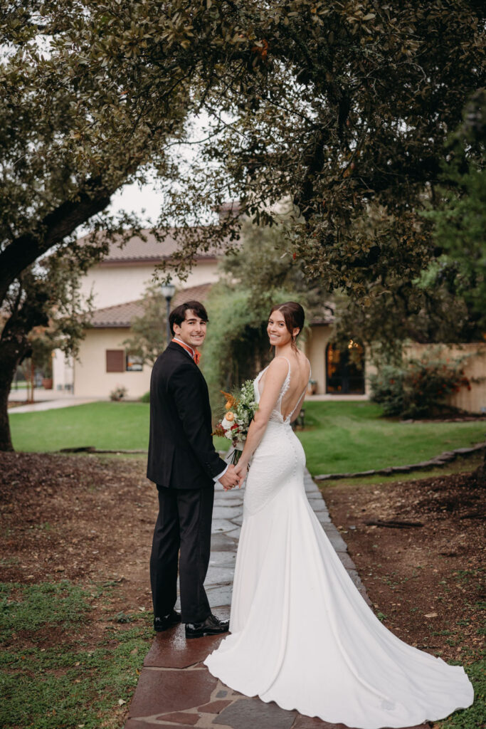 A newlywed couple shares a joyful moment under the trees at Ma Maison