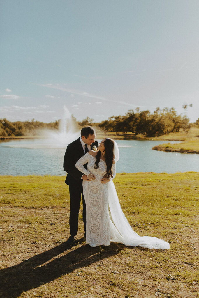 A newlywed couple embraces near the lake at Ma Maison