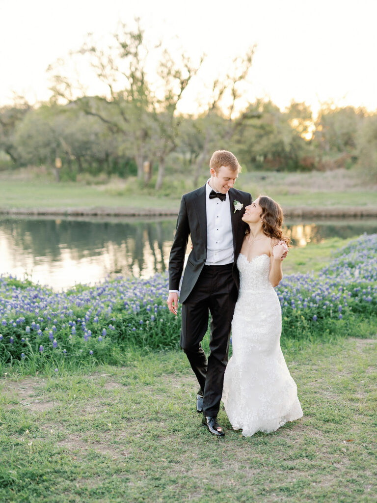 groom and bride walking by the pond at Ma Maison in Dripping Springs, Texas