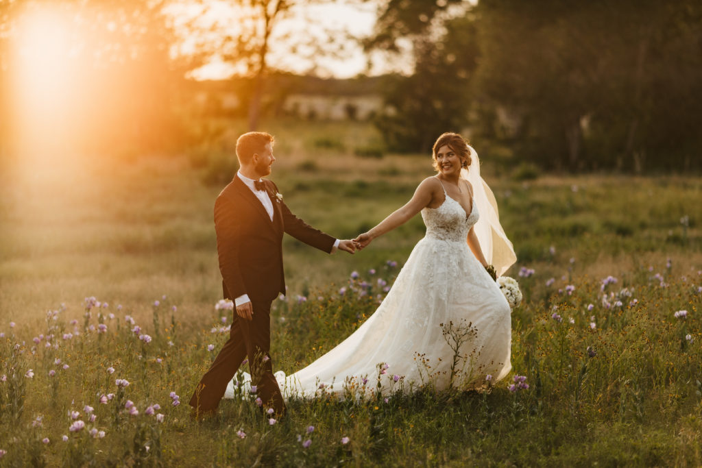 bride and groom walking through grass at Ma Maison wedding venue in Dripping Springs, Texas
