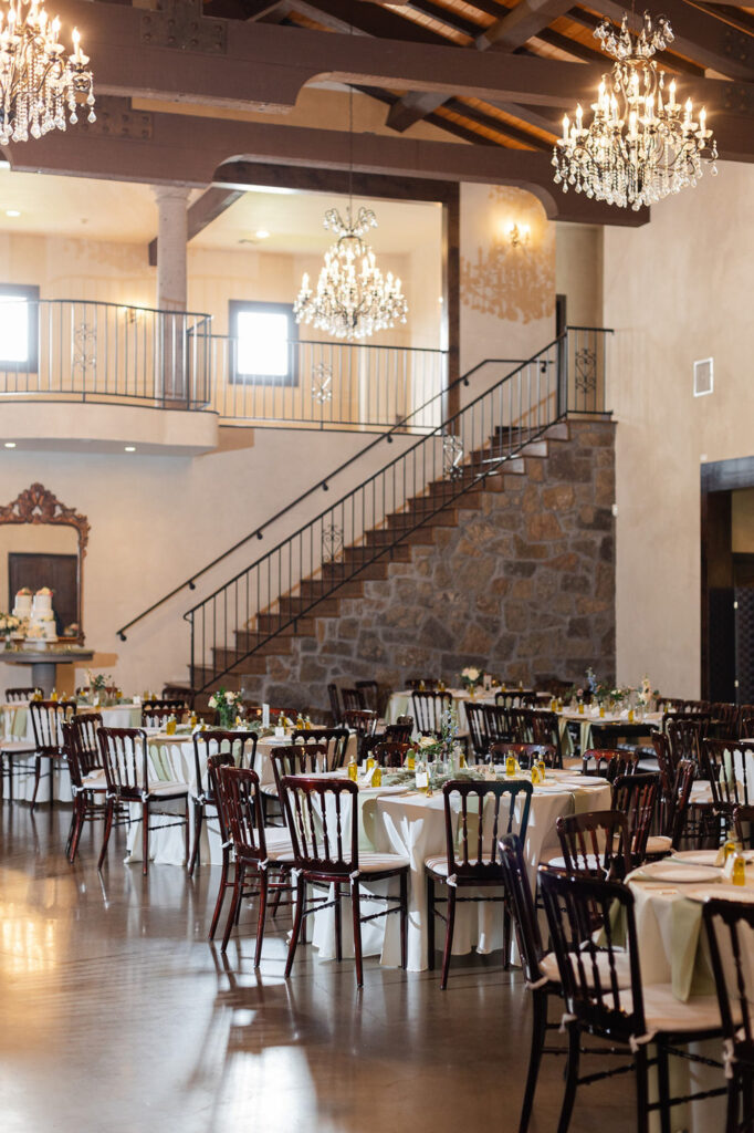reception hall with banquet tables and chandeliers at Ma Maison, a wedding venue in TX
