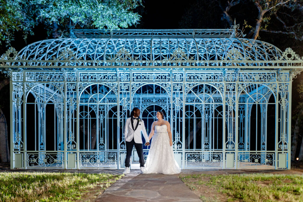 bride and groom standing in front of greenhouse