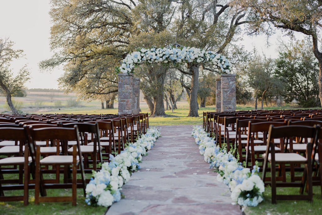 Outdoor ceremony aisle with white and blue florals at a luxury Austin wedding venue
