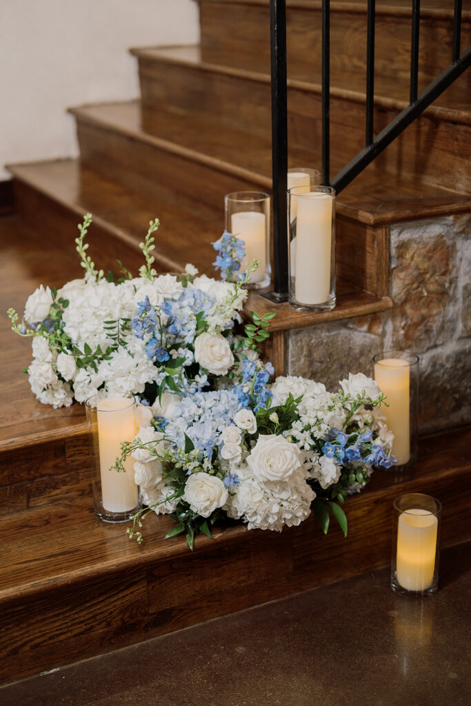 Staircase decorated with white and blue florals and candles
