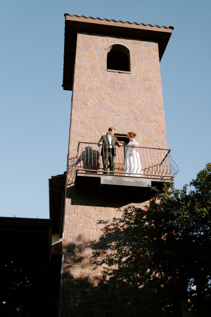 Bride and groom standing on the stone tower balcony at Ma Maison.