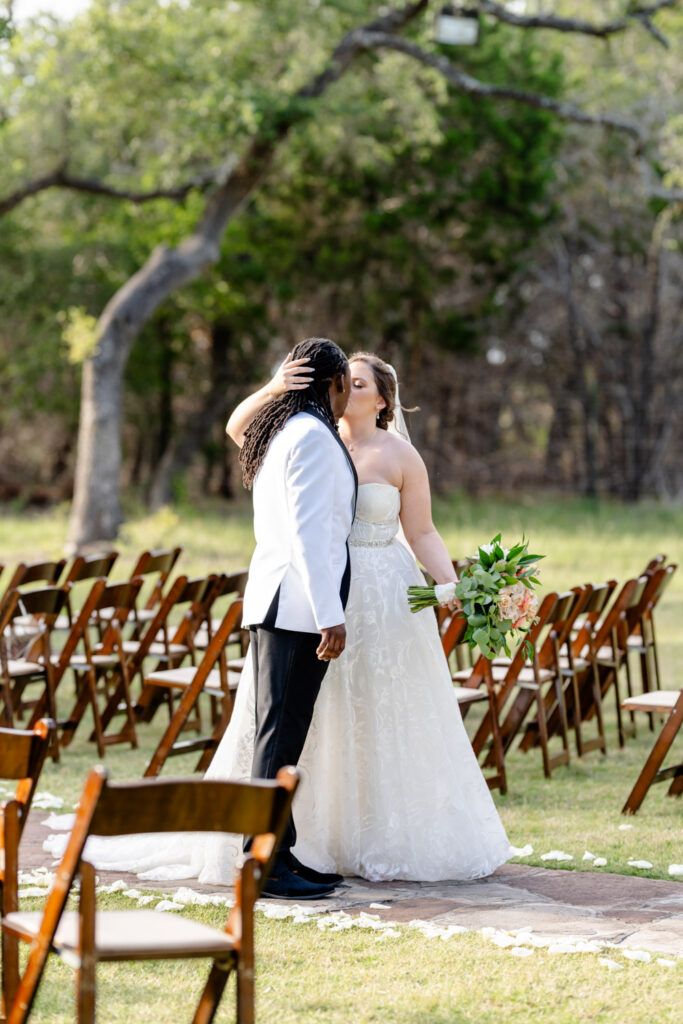 The bride and groom kiss along the ceremony aisle