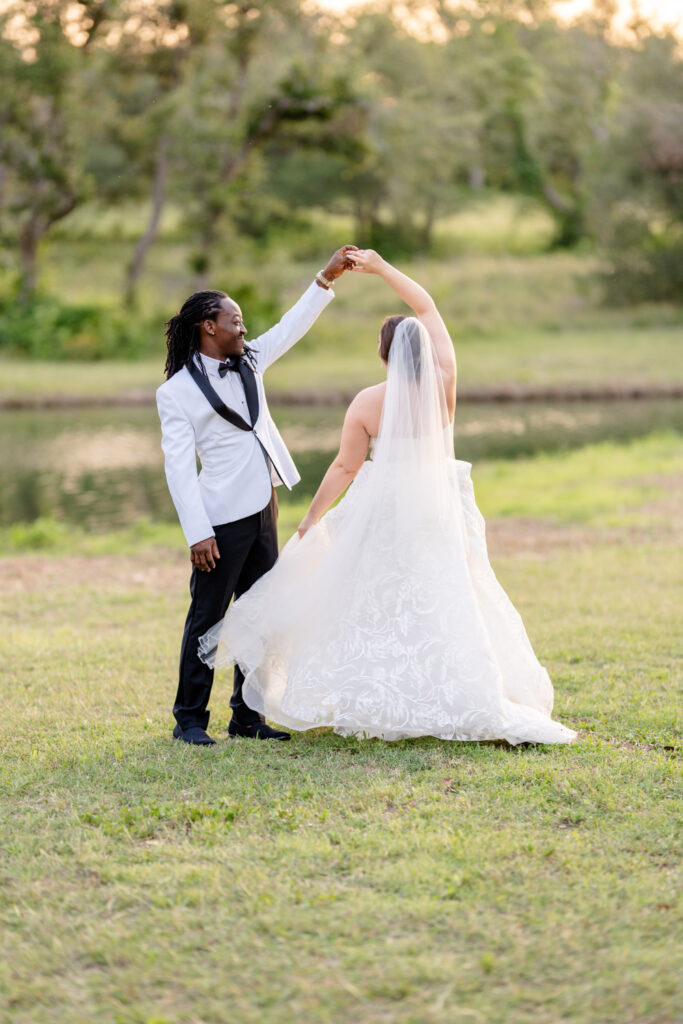 The groom twirls the bride during sunset near the pond at Ma Maison Austin Wedding Venue